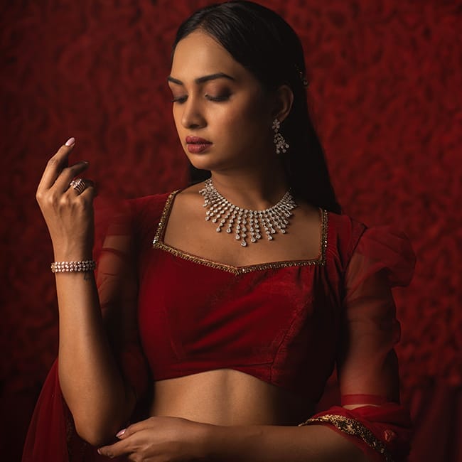 A bride poses with a bridal diamond necklace, diamond bangle, diamond ring, and diamond earrings.