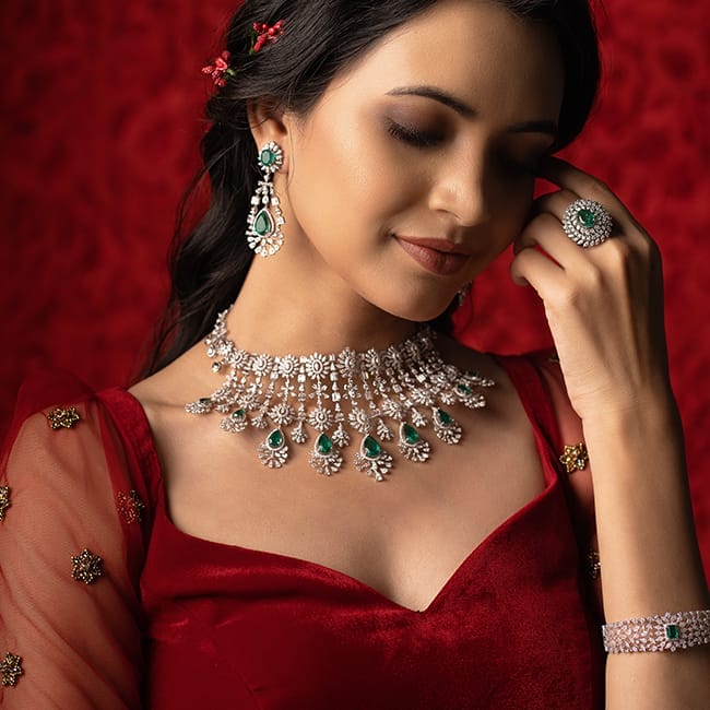 A modern bride wearing a bridal necklace, bangles, ring, and earrings studded with diamonds and green gemstones.