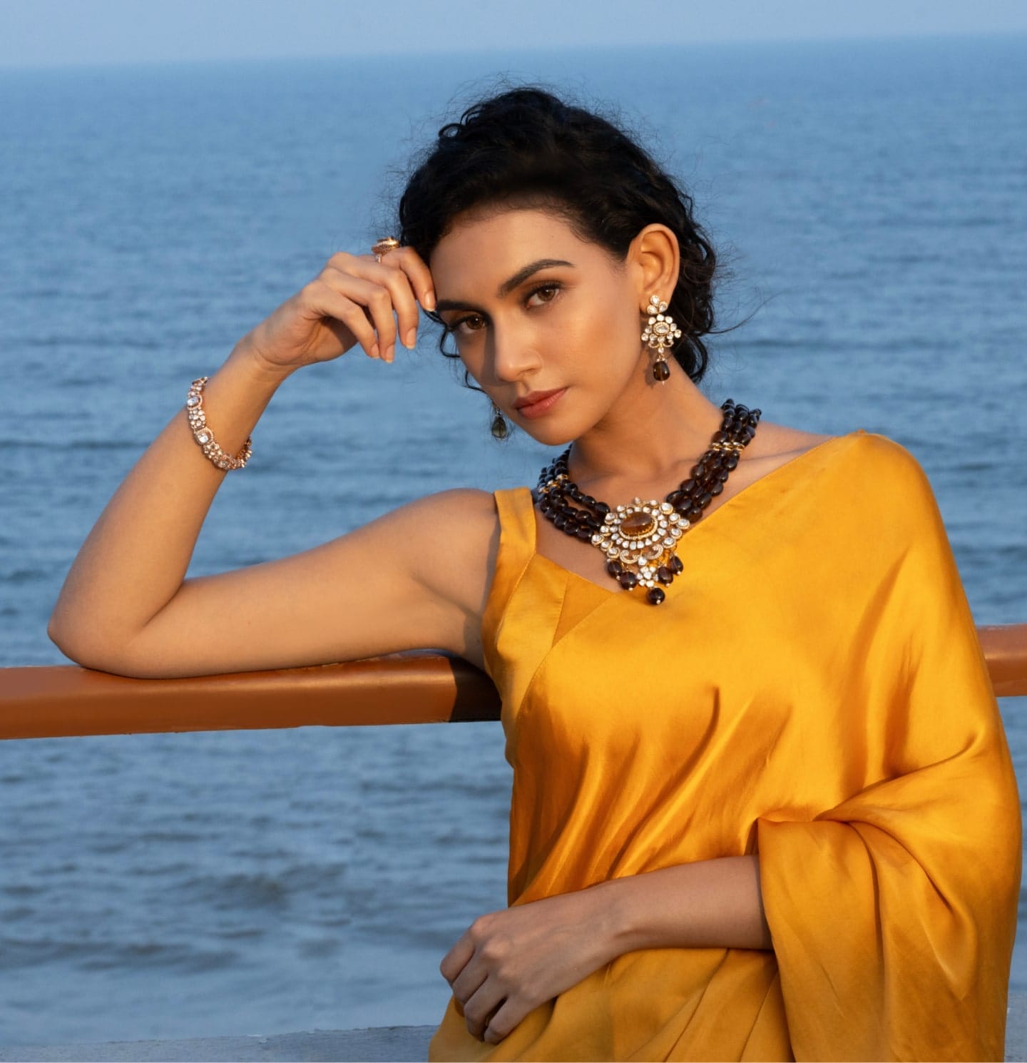 A modern maid in a mustard color saree adorning herself with stunning uncut diamond polki jewellery with precious gemstones from the Fazza Collection by Khwaahish.